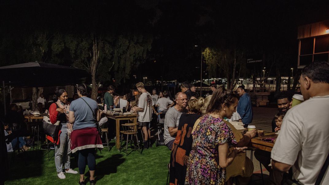 People as part of the Majestic Church community gather for a meal on a lawn.